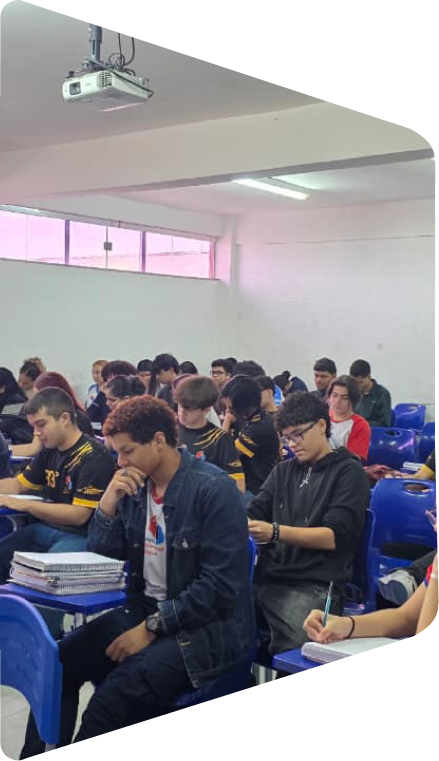 Estudantes do Ensino Médio em sala de aula, sentados em carteiras azuis